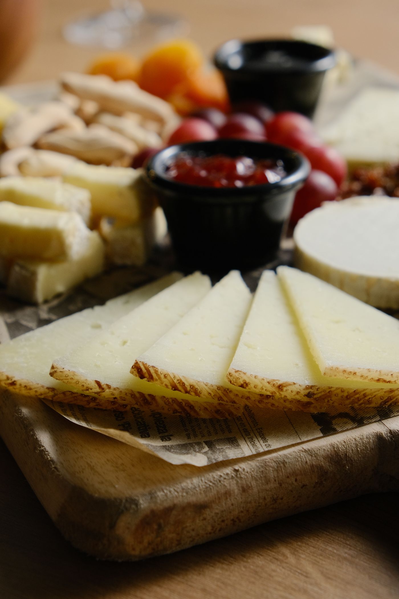 Elegante kaaswiggen op een plank met jam en druiven